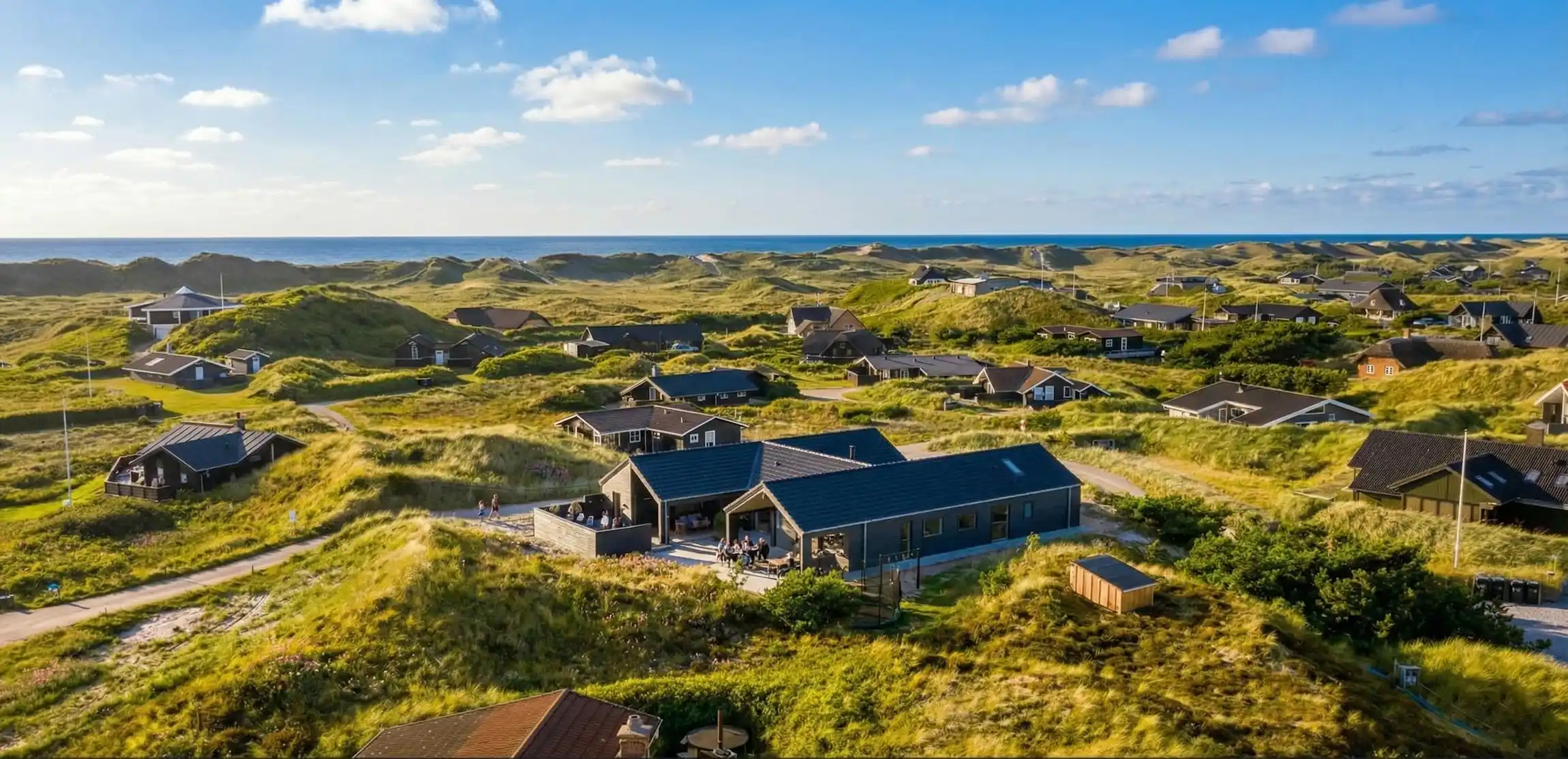 VillaVilla luksus-sommerhus i sommerhusområde med klitter og blå himmel