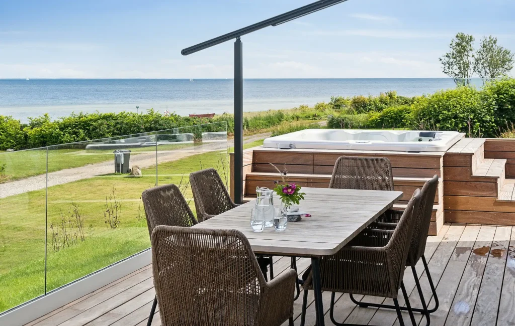 sommerhus ved havet med træterrasse, spisebord, udespa og havudsigt