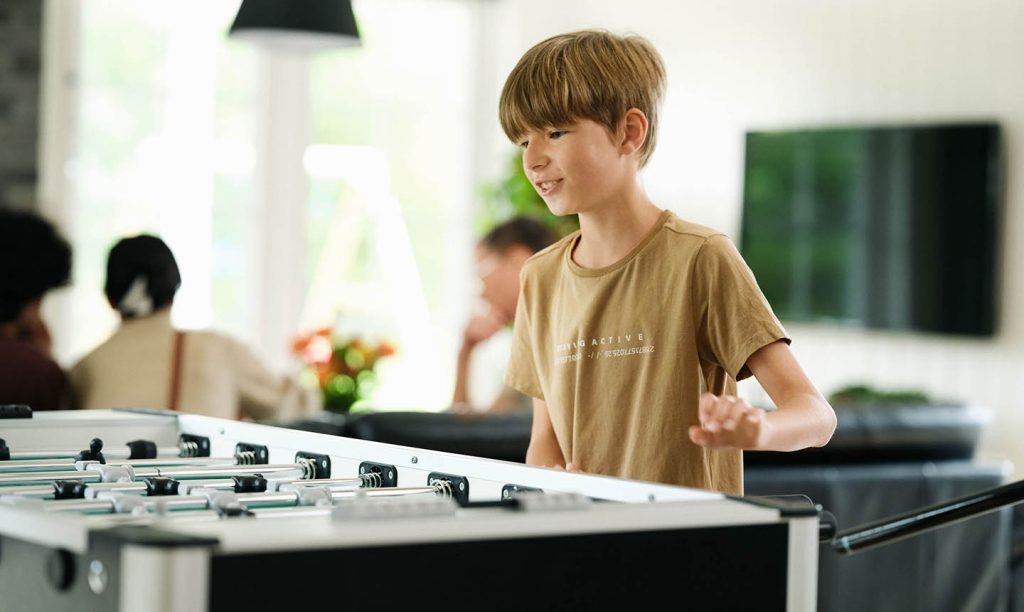 dreng ved bordfodboldbord i sommerhus