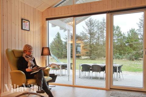 Stuen, som har udsigt til haven, er smagfuldt indrettet med komfortable møbler, brændeovn og et stort fladskærms-tv