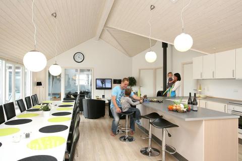 Huset er indrettet med et lyst opholdsrum med køkken, spisepladser og sofagruppe med brændeovn