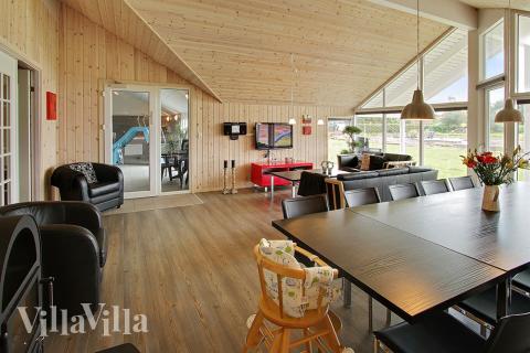 Opholdsrummet med det store vinduesparti er husets naturlige samlingspunkt med spisepladser og sofagruppe med fladskærms-tv