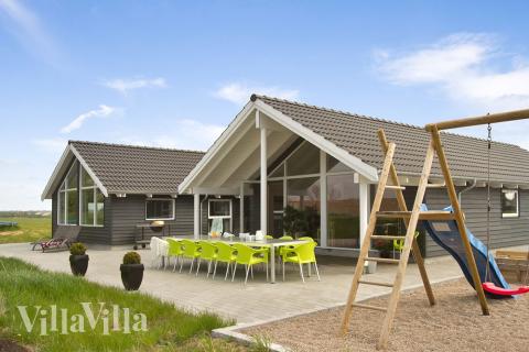 På husets grund er der opført gyngestativ og sandkasse. Så kan børnene lege mens de andre familiemedlemmer nyder solen på husets store terrasse.