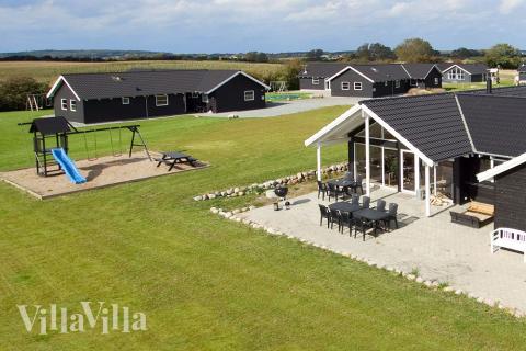 På husets grund er der opført gyngestativ og sandkasse. Så kan børnene lege mens de andre familiemedlemmer nyder solen på husets store terrasse.
