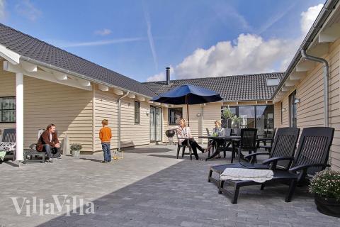 Udenfor kan der grilles på den delvist overdækkede terasse. De mindste kan fortsætte legen på græsset, i gyngerne, på trampolinen og i sandkassen