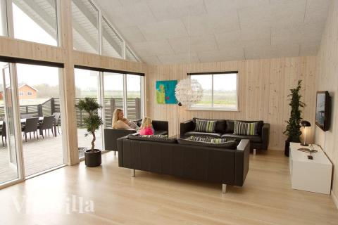 Stuen ligger i forbindelse med køkkenalrummet - og her kan I tænde op i brændeovnen og slænge jer i sofaen