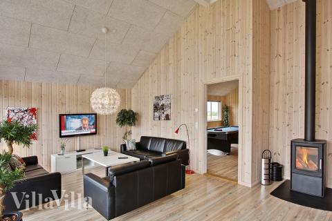 I det centrale køkken-alrum er der indrettet en sofagruppe med brændeovn, som indbyder til afslapning med en god bog eller film