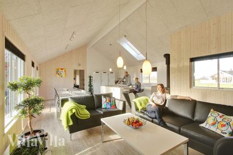 Husets køkken-alrum er hyggeligt indrettet med komfortable møbler, brændeovn og spisepladser 