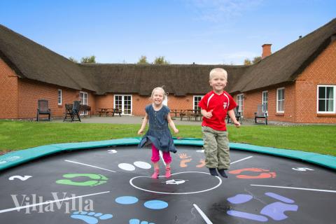 Den indbydende og store fliseterrasse ligger godt i læ mellem husets længer