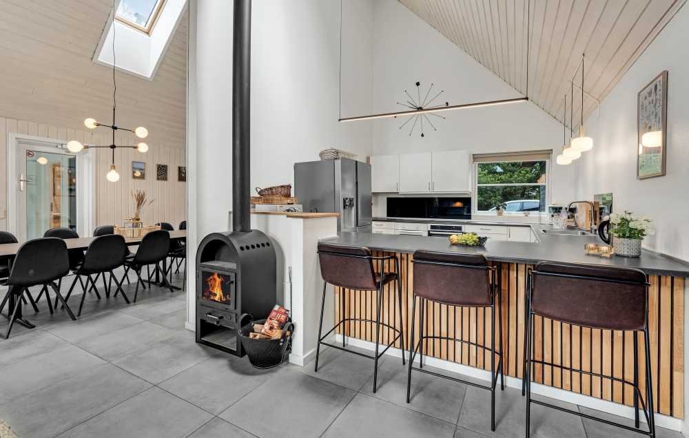 Brændeovnen er placeret tæt på både spisepladser, sofagruppe og køkken og kan sørge for lidt ekstra varme og hygge på en kølig dag
