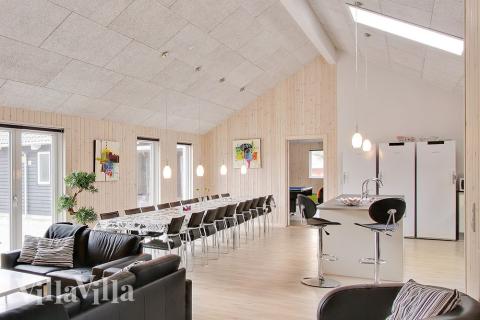 Det centralplacerede køkkenalrum er indrettet med et rummeligt køkken, spisepladser og sofagruppe 