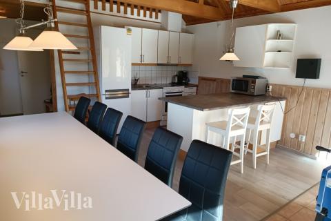 Opholdsrummet i stueetagen er indrettet med køkken, spisepladser og brændeovn