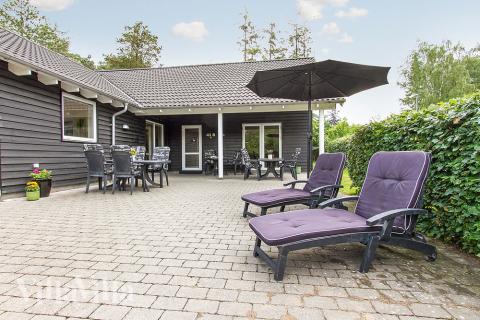 På den store terrasse kan sommerdagene nydes i gode havemøbler, mens børnene kan lege i legehuset, på græsplænen eller i sandkassen