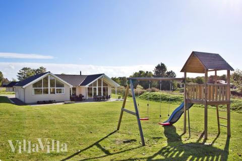 På husets grund er der opført gyngestativ og sandkasse. Så kan børnene lege mens de andre familiemedlemmer nyder solen på husets store terrasse.