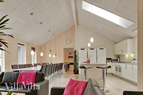 Huset er indrettet med et lyst opholdsrum med køkken, spisepladser og sofagruppe med brændeovn