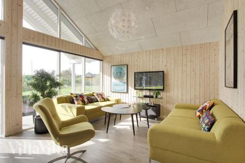 Stuen, som har udsigt til haven, er smagfuldt indrettet med komfortable møbler, brændeovn og et stort fladskærms-tv